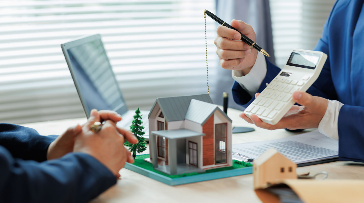 Jeune couple assis devant un ordinateur portable affichant un simulateur de prêt immobilier avec mentions PTZ et aides publiques en français sur l'écran
